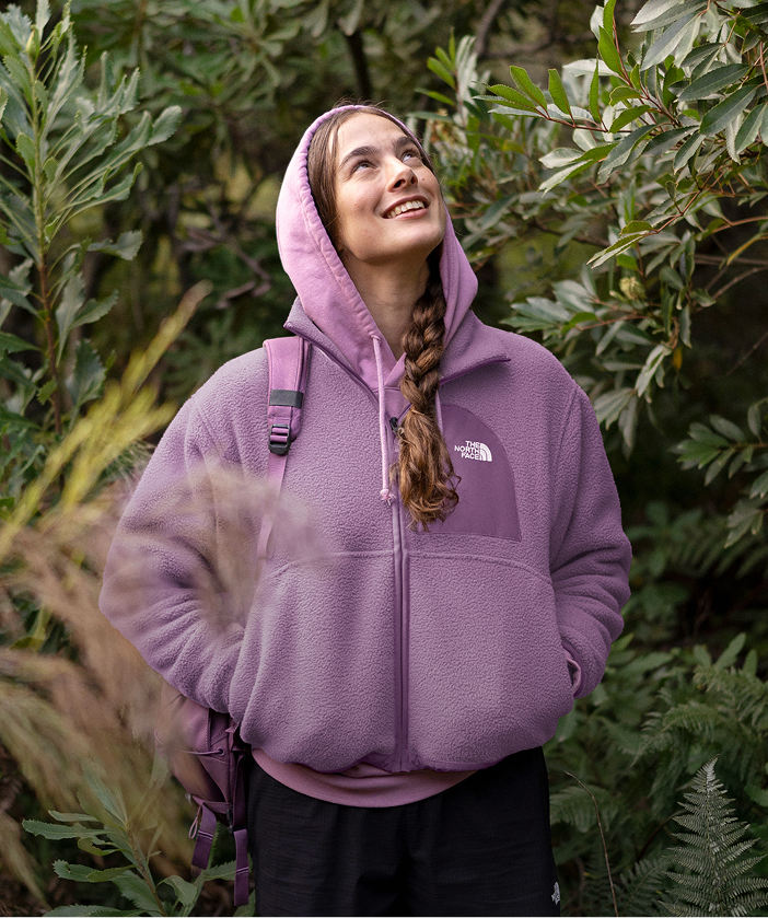 Young person in purple fleece smiling and looking upward.