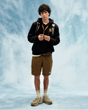 Young person wearing black hoodie and tan shorts