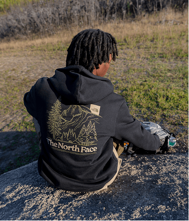 A kid's back facing the camera featuring a branded TNF black hoodie.