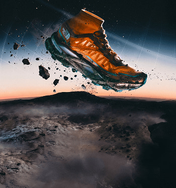 Orange Offtrail Ultra shoe suspended above mountainous terrain with the sunset in the background.