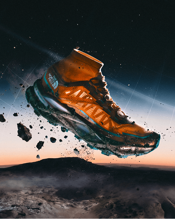 Orange Offtrail Ultra shoe suspended above mountainous terrain with the sunset in the background. 