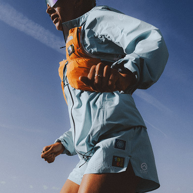 Closeup of a person running, wearing an orange Summit Series™ Run Vest.