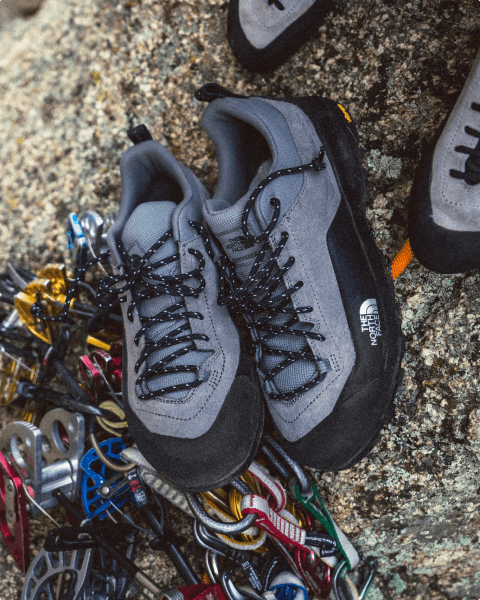 Close up of north face climbing shoes next to climbing gear.