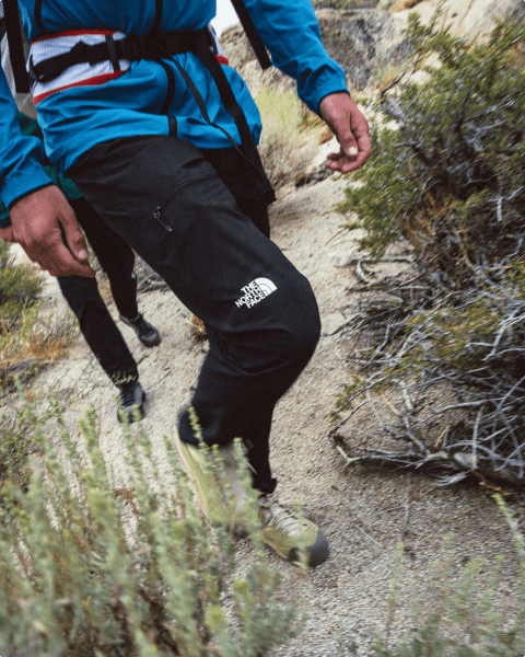Close up of a person wearing black North Face climbing pants on a trail.