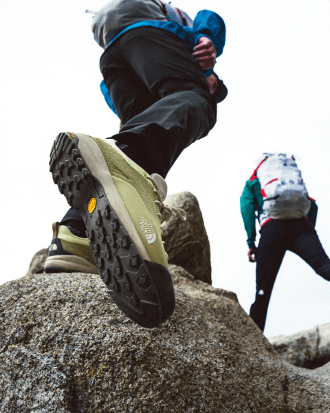 close up shot of a person wearing green North Face climbing shoes