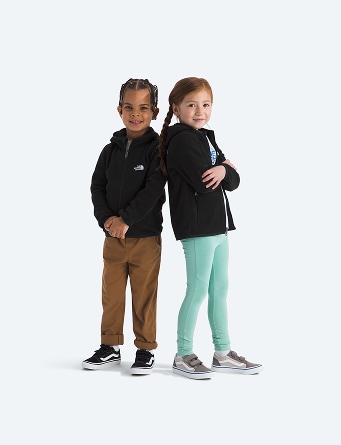 Deux enfants posant devant la caméra portant des vestes noires à fermeture éclair intégrale.