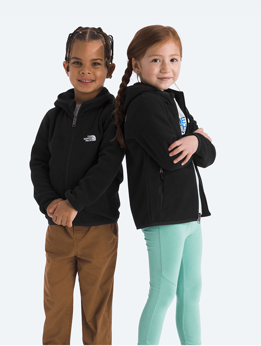 Two kids posing for the camera wearing black full zip jackets