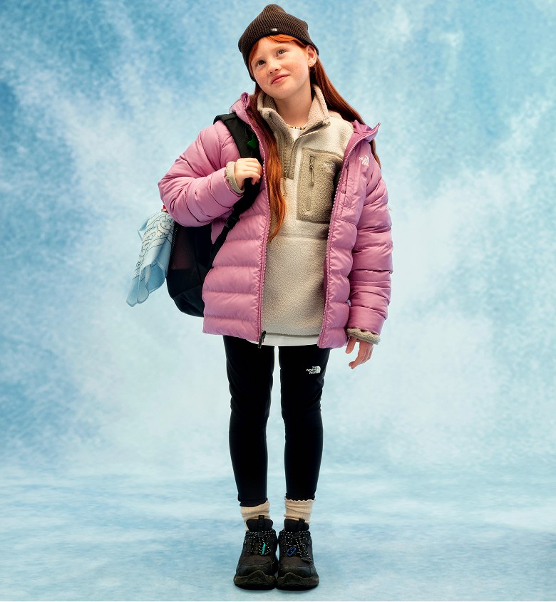 A 3-photo layout of three different children. The first image shows a child wearing a blue hat, brown shirt, brown pants, black shoes and a black backpack. The second image shows a child wearing a green puffer coat, black pants and black shoes, holding yellow headphones. The third image shows a child wearing a brown fleece with a purple puffer jacket, black pants, black shoes and a black backpack.
