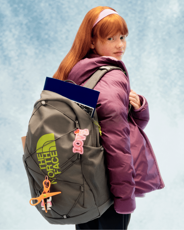 A young girl looking over her right shoulder, wearing a grey Jester backpack