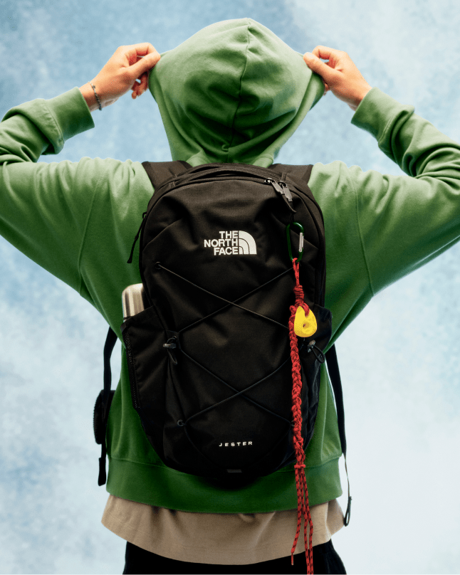 A man's back facing the camera, wearing a black Jester backpack