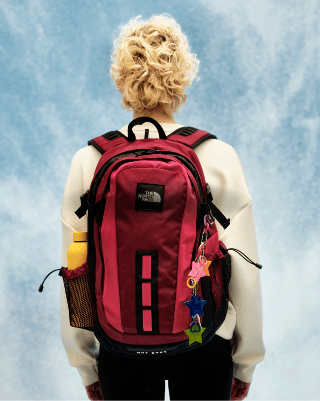 A woman's back facing the camera, wearing a red Hot Shot backpack