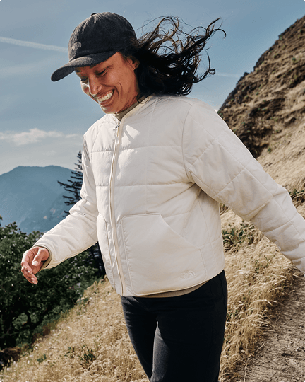 A woman walking down a hill wearing a white Lhotse