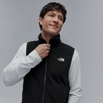 A man zipping up a black vest
