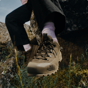 A woman sitting on a rock wearing North Face shoes
