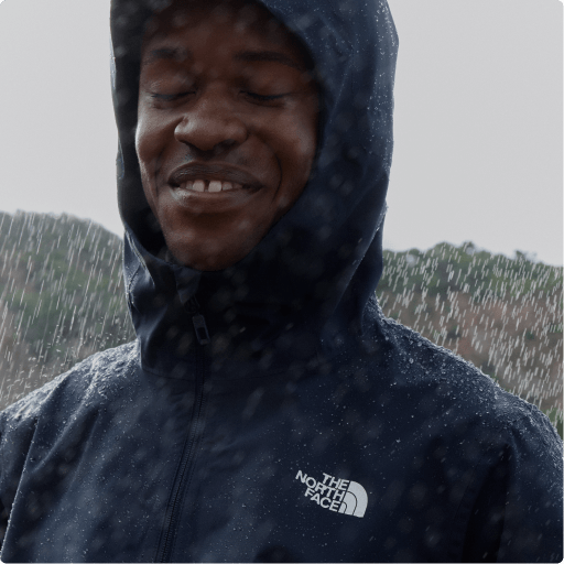 A man wearing a rain jacket smiling in the rain