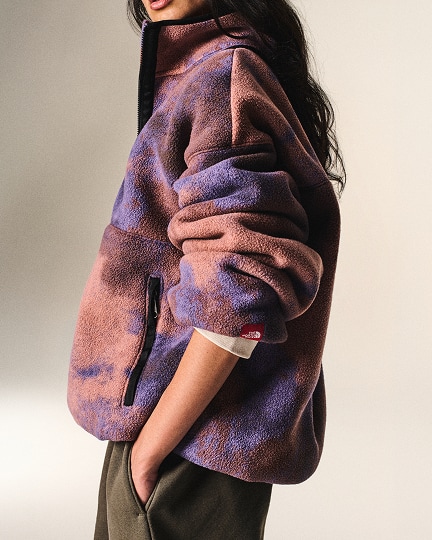 Une femme posant vêtue d’un manteau en laine polaire orange et violet de la collection Red Box de The North Face