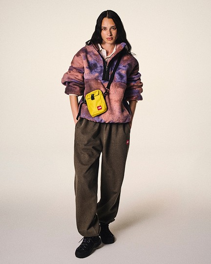 Une femme posant vêtue d’un manteau en laine polaire orange et violet de la collection Red Box de The North Face