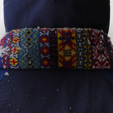Close-up of the back of the colorful jacquard scarf with snow on it, with white background.