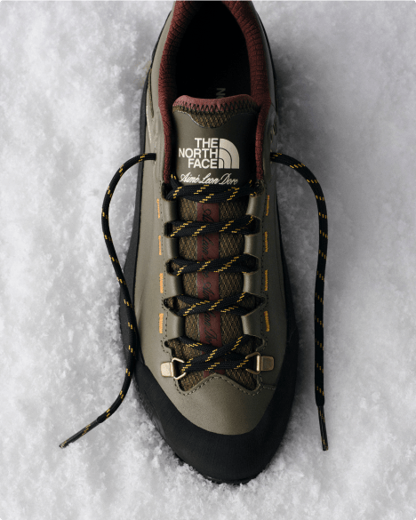 Over head shot of an unlaced hiking shoe on snow.