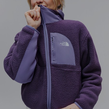 A person zipping up a purple Yumiori fleece.