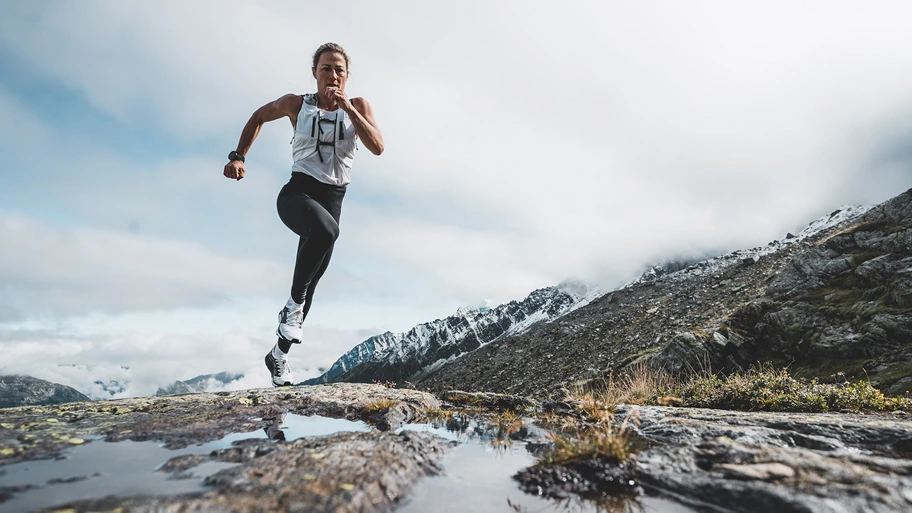 A runner strides across cold mountain terrain.