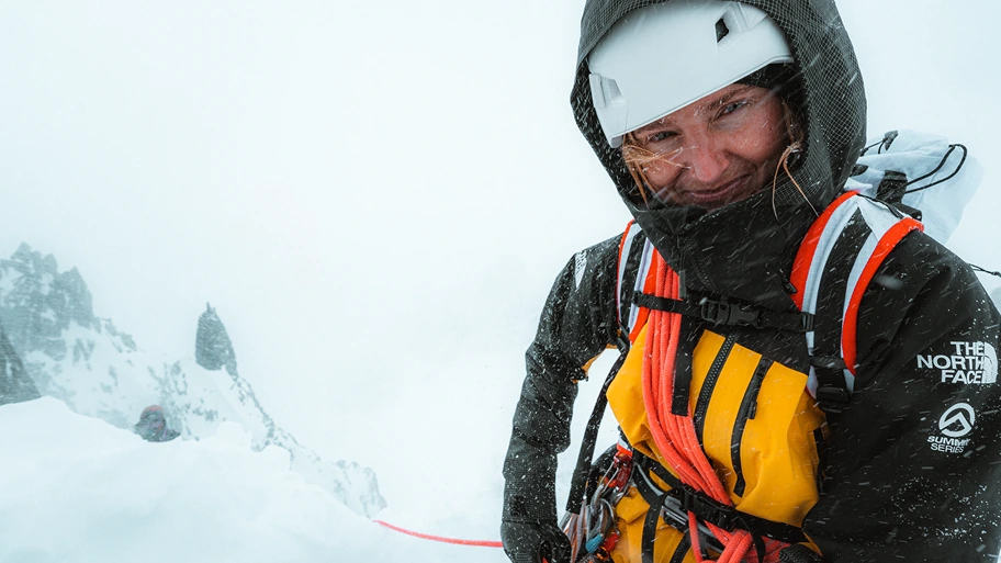 An athlete in cold weather gear poses near a winter storm.
