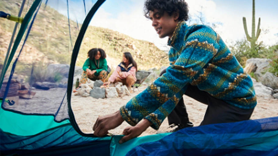A camper packs a tent in a desert camp site.