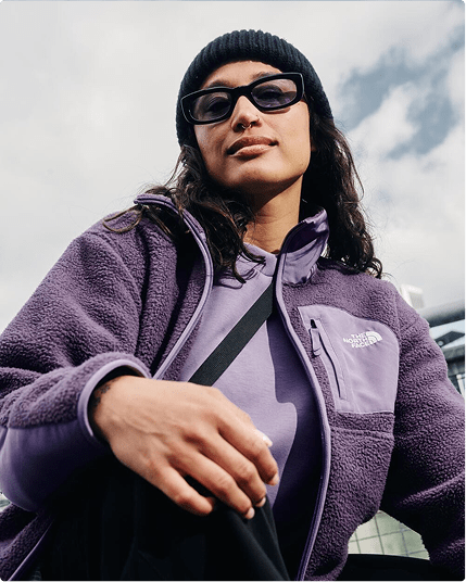 Person reclining on the ground wearing a purple fleece jacket.