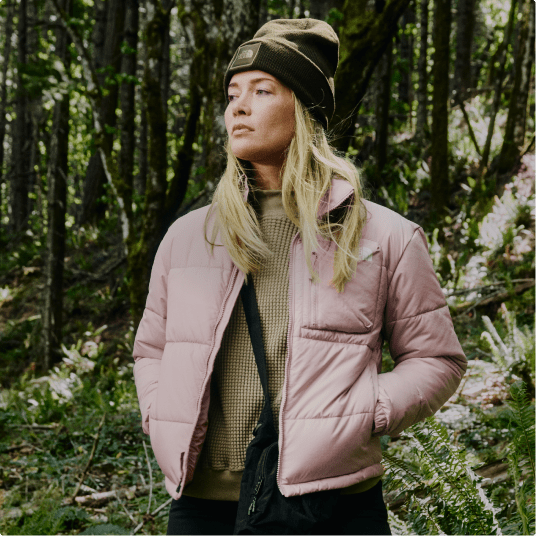 A person wearing a pink jacket is standing in the forest.