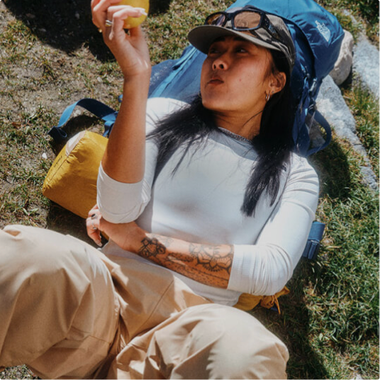 A person in a white long-sleeved shirt is lying on the ground looking off to the side. 