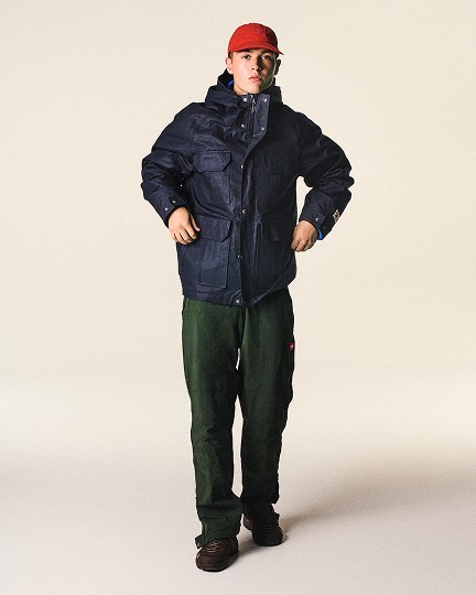 Man in studio wearing blue jacket red hat.