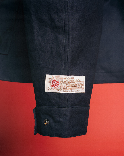 Man in studio wearing blue jacket red hat.