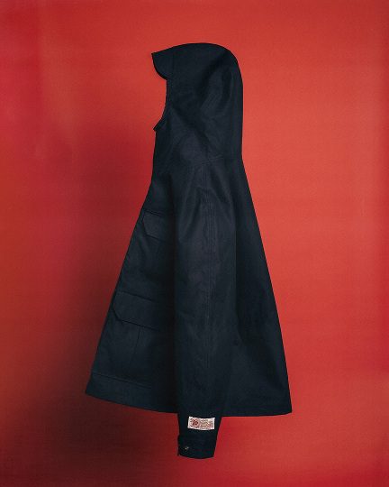 Man in studio wearing blue jacket red hat.