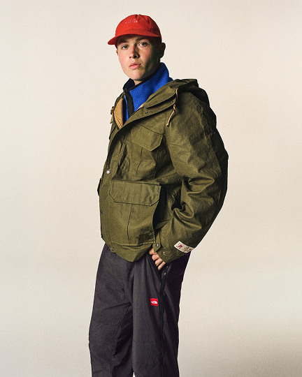 Man in studio wearing blue jacket red hat.