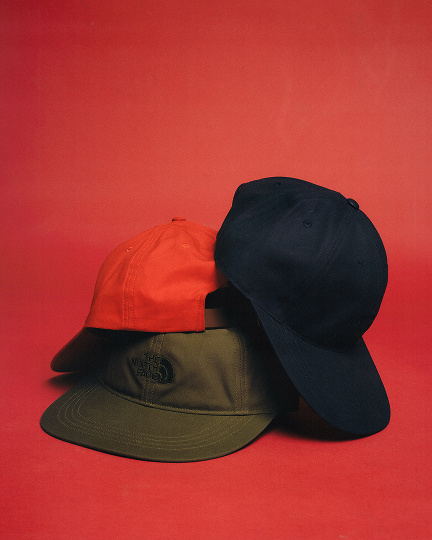 Man in studio wearing blue jacket red hat.