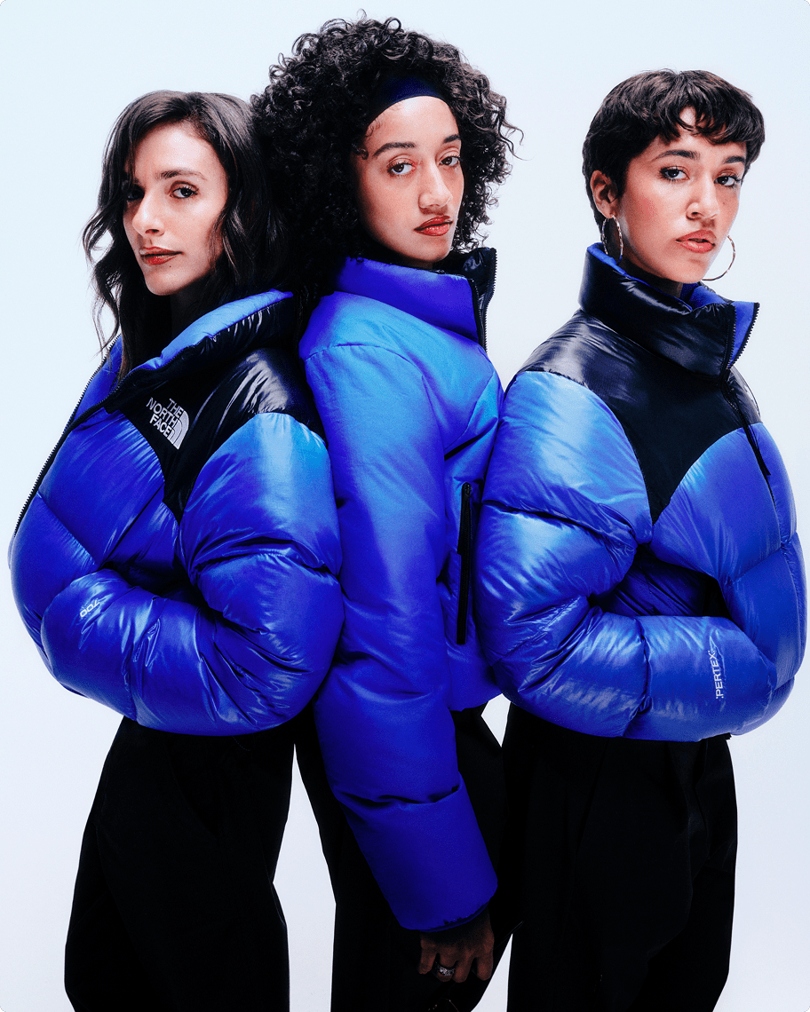 The DJ trio Las Flaquitas are standing next to each other, all wearing blue Pertex Nuptse jackets.