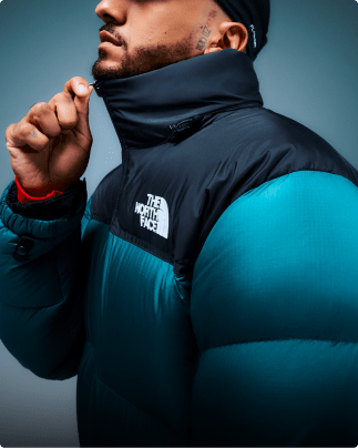 A teal 1996 Closeup of a person wearing a teal 1996 Retro Nuptse jacket. Nuptse is suspended in air on a white background.