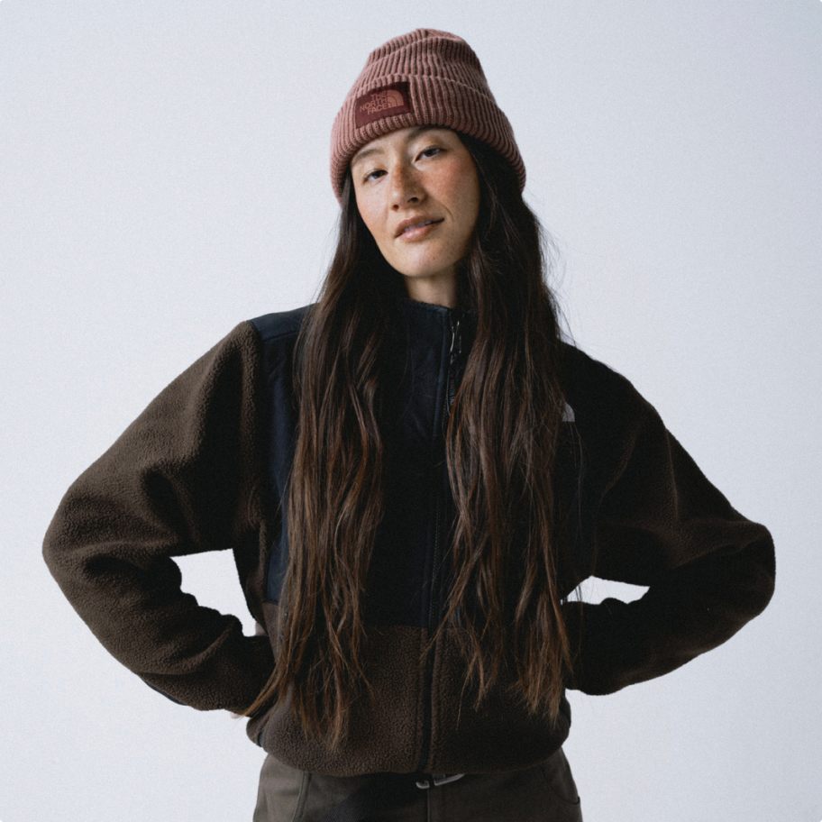 Woman posing in a North Face beanie and black long sleeve.