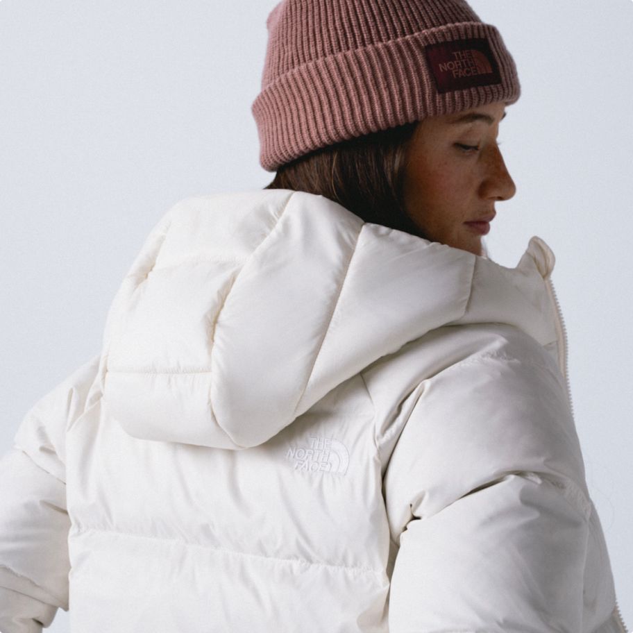 Woman's back turned towards the camer wearing a beanie and white jacket.