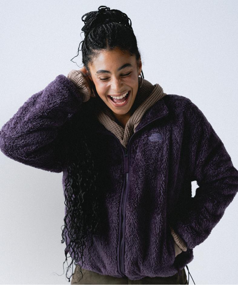 Woman wearing high-pile purple fleece zip-up, oatmeal color thermal underneath, with khaki pants.