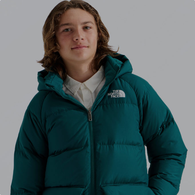 A boy wearing a teal insulated jacket from The North Face.