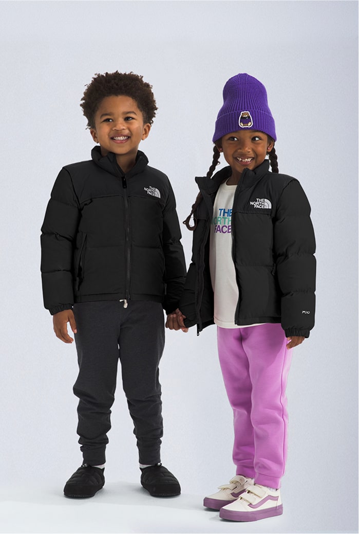 Two little kids wearing black Nuptse jackets.