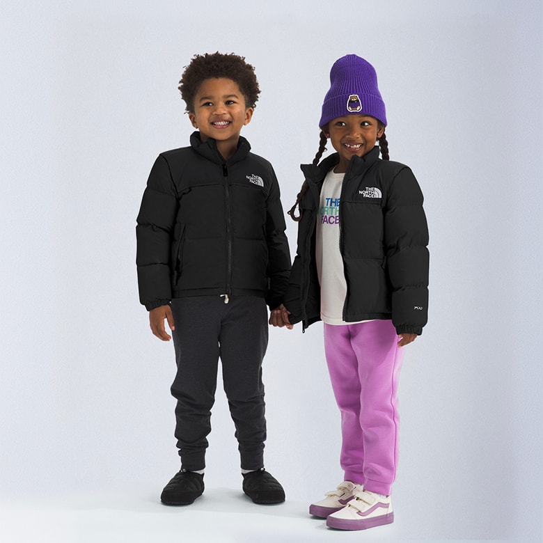 Two little kids wearing black Nuptse jackets.
