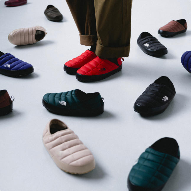 A man wearing red Thermoball Mules surrounded by other Thermoball mules.
