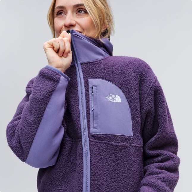 A woman zipping up her purple Yumiori fleece.