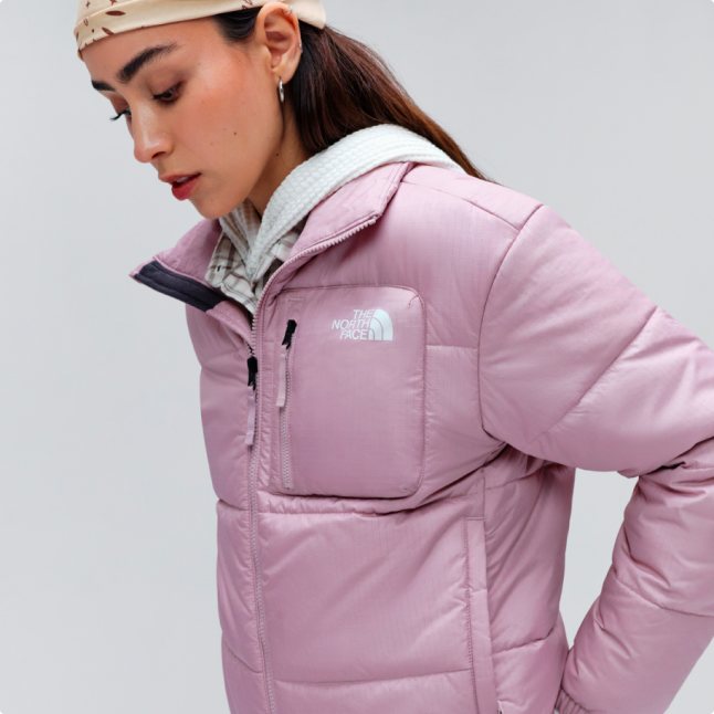 A woman looking down wearing a pink Nuketo insulated jacket.