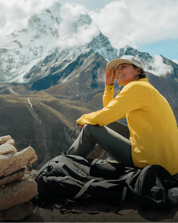 Hilaree sitting next a mountain looking back.