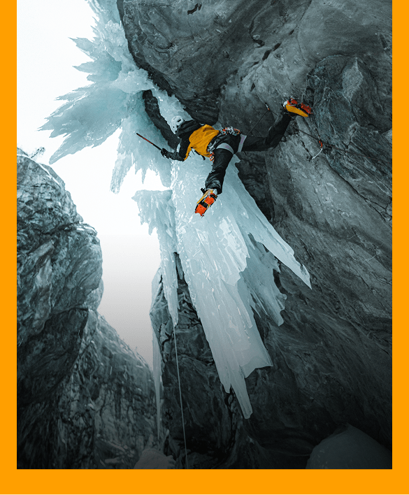 North Face Athlete Ice climbing up a mountain wearing gold summit series clothing.