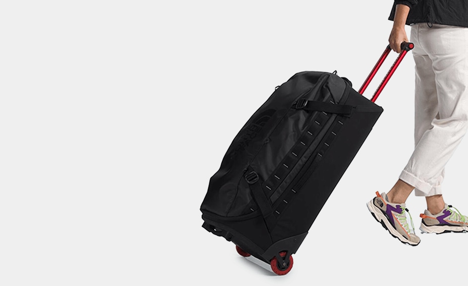 A studio shot of someone wheeling the Base Camp Rolling Thunder luggage.