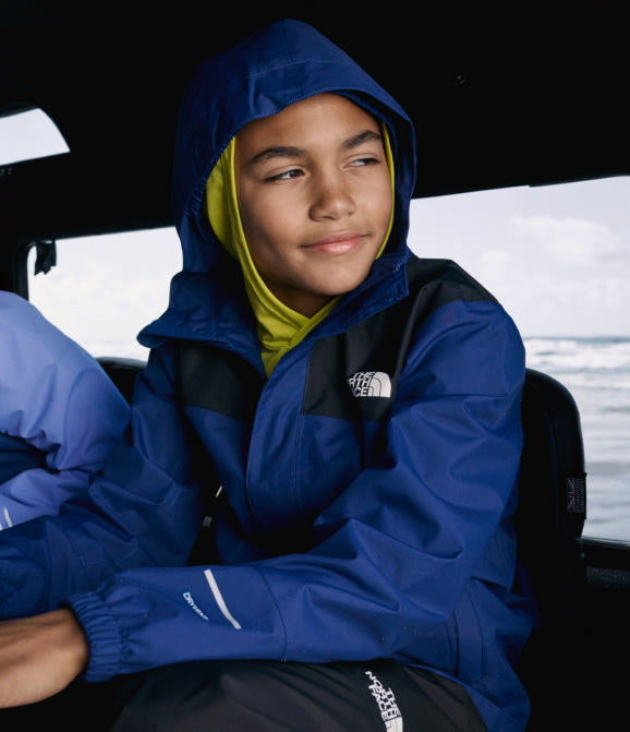 A young boy wearing a rain jacekt from The North Face.